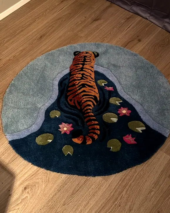 Rundt teppe med en tiger som drikker fra en dam med vannliljer